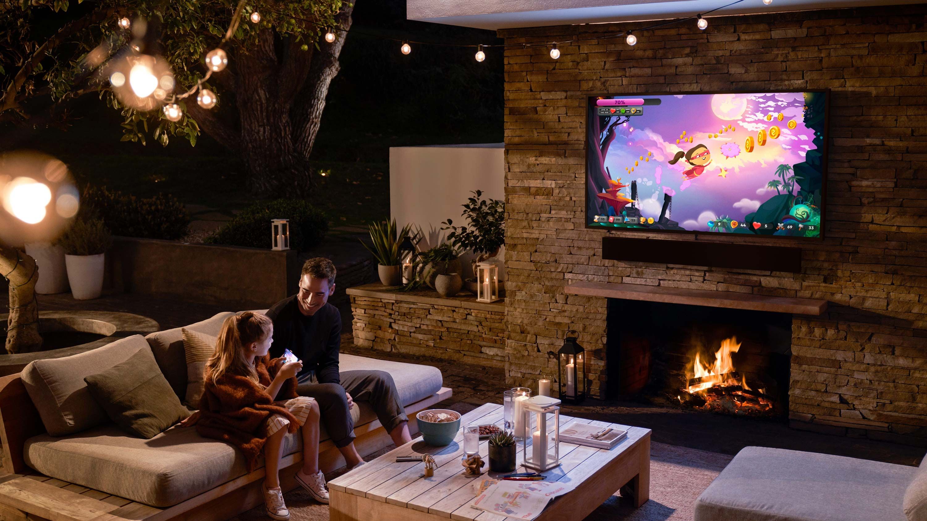 father and daughter sitting on patio watching tv on samsung technology